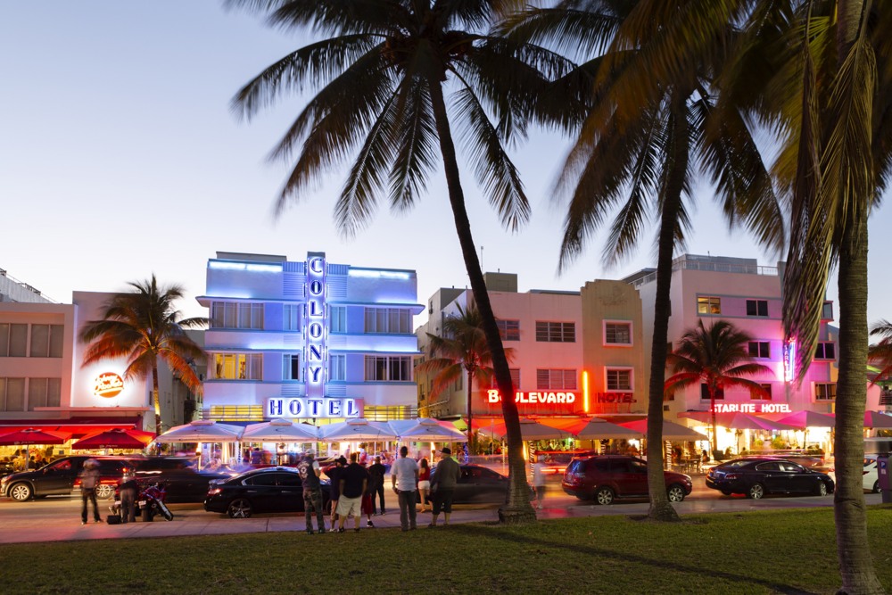 Das Bild zeigt eine Häuserzeile mit Palmen und Neonlicht in Miami Beach, fotografiert von Jörg Modrow.